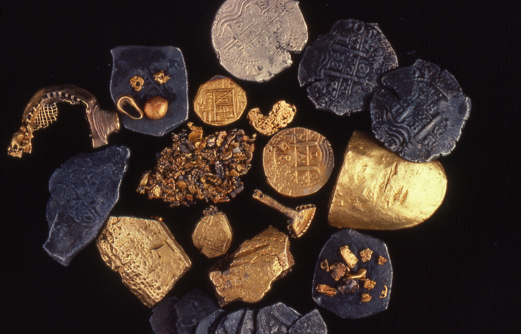 Assorted ancient coins and gold artifacts on a black background.